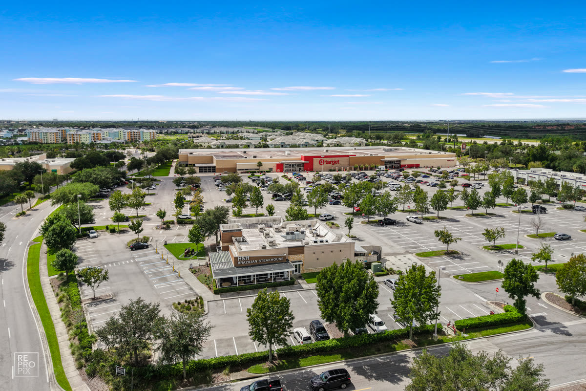 Aerial view of a retail shopping center with extensive parking and a wide horizon — commercial drone photo