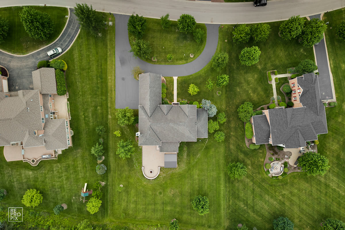 Top-down aerial view of neighboring homes, lawns and a curving street — drone photography