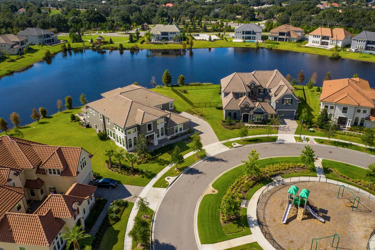 Aerial view of a lakeside residential community with tile-roofed homes and a central green