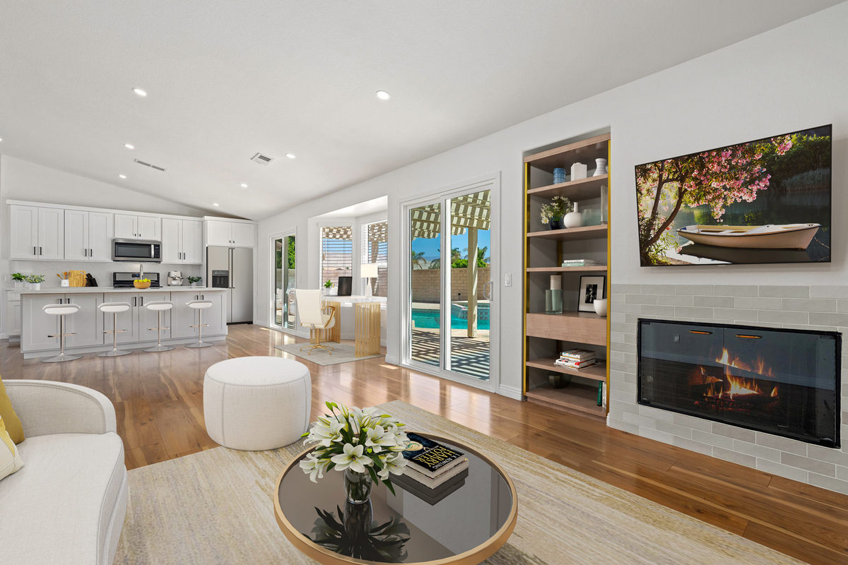Open-plan kitchen and living room with white cabinetry and a pool view through glass doors