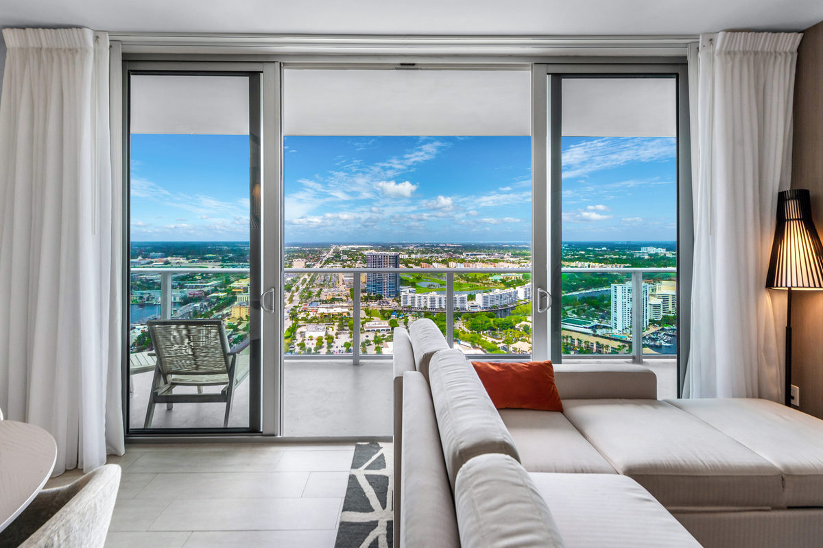 High-rise living room with floor-to-ceiling glass and a balcony overlooking the coast