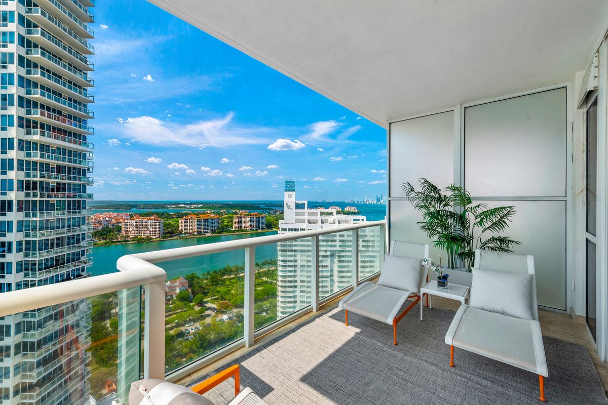 High-rise balcony with loungers overlooking a marina and the bay