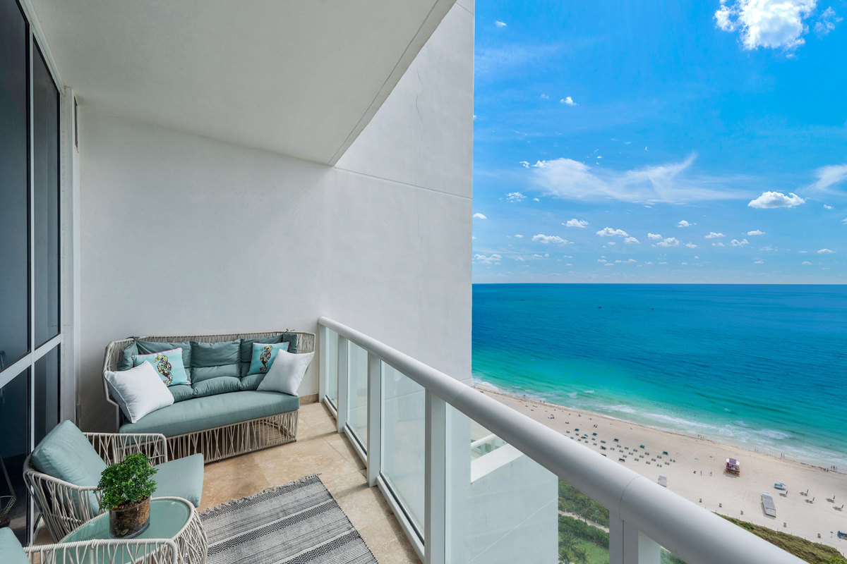 Covered balcony with seating overlooking a beach and the ocean