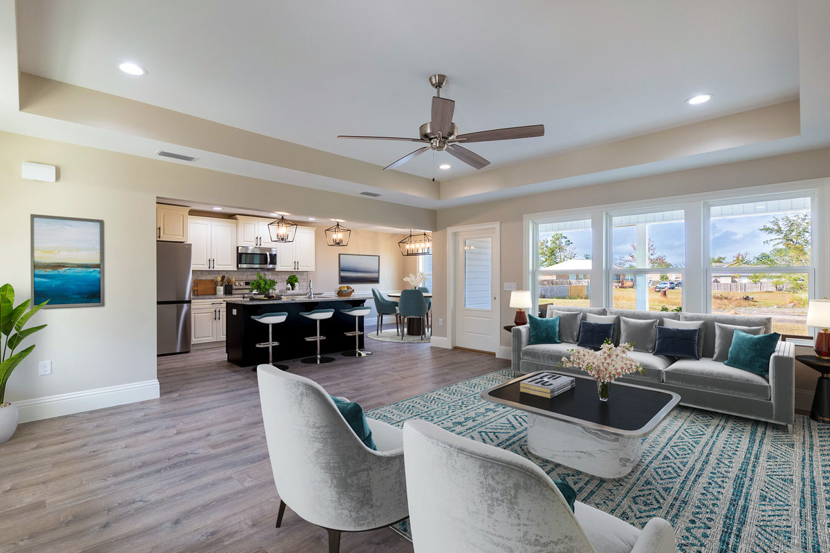 Open living and dining area with a ceiling fan, grey flooring and waterfront windows