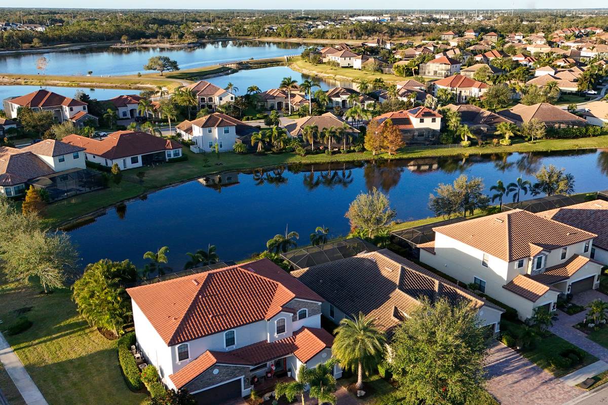 Aerial view of lakeside homes with tile roofs and mature landscaping