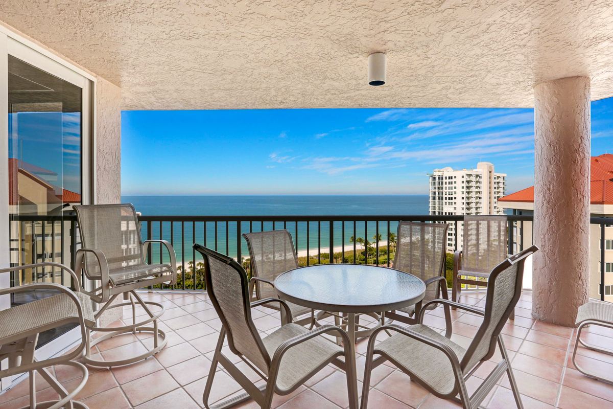 Tiled terrace with a dining set overlooking the shoreline and the coast beyond