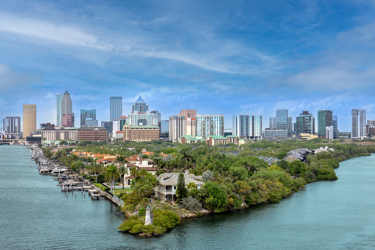 Aerial view of a city skyline across the water with waterfront homes and mangroves