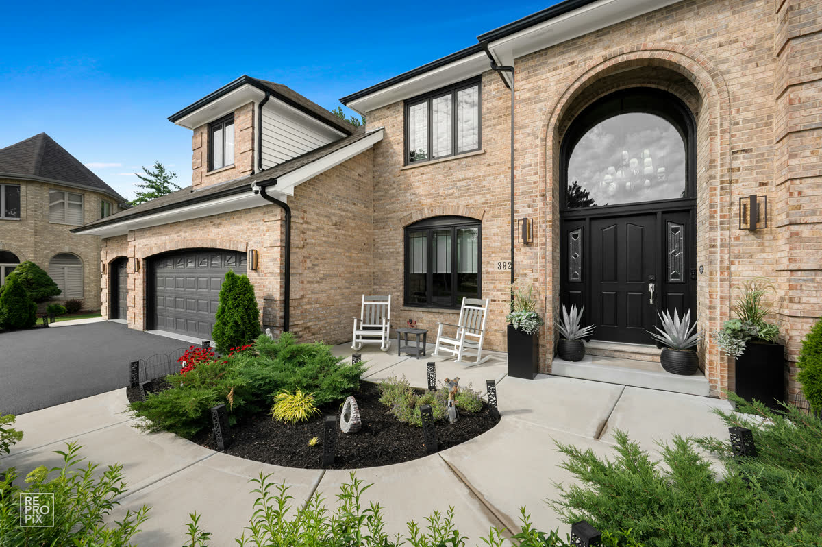 Brick two-story Chicago-area home with an arched entry and landscaped front walk — home exterior photo