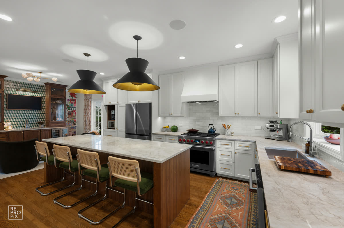 Kitchen with a large island, black pendant lights and bar seating — listing photo