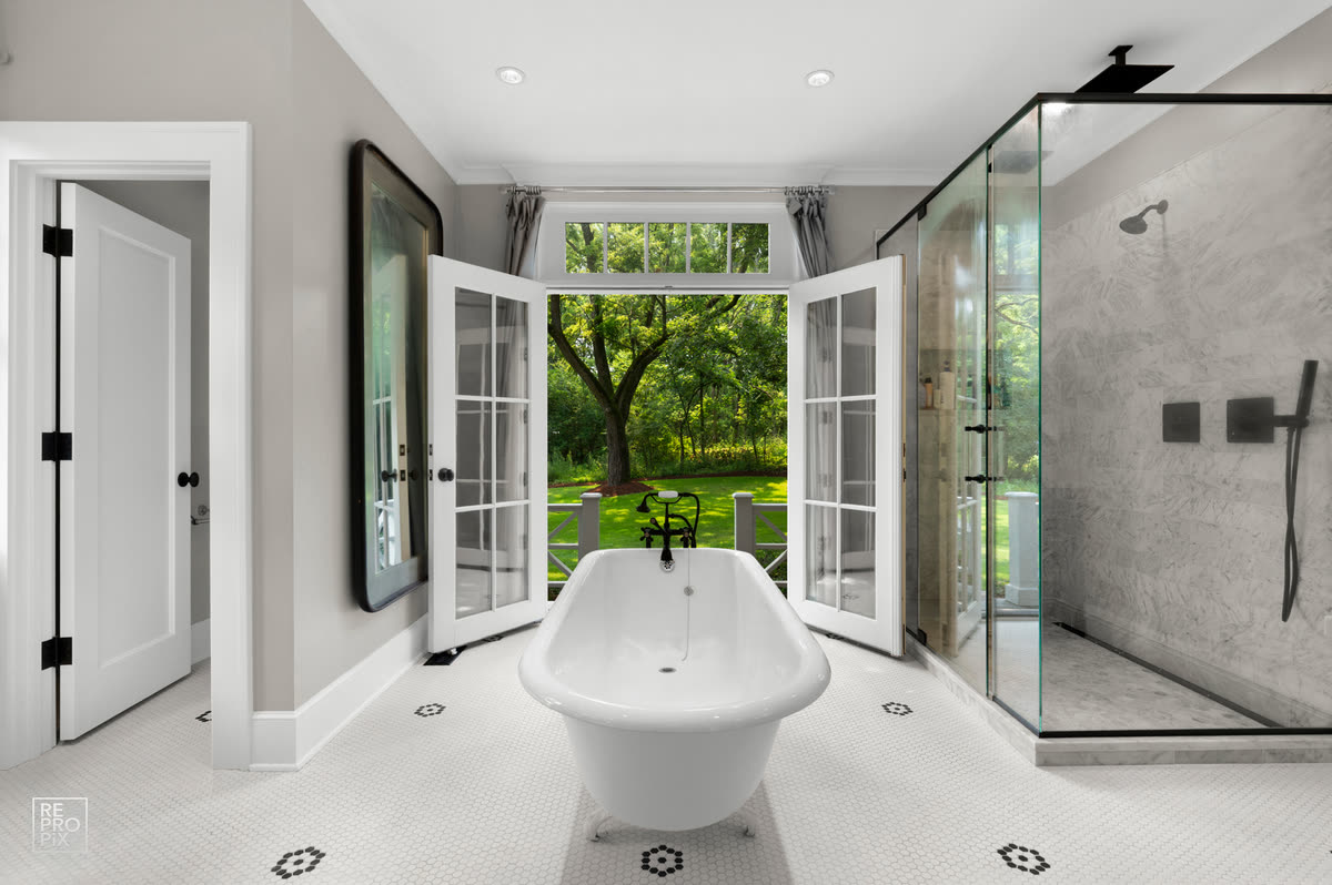 Bathroom with a freestanding tub, French doors opening to the garden and a glass shower — property photo