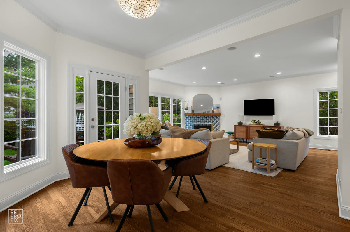 Round dining table with leather chairs, open to the living room and French doors — listing photo