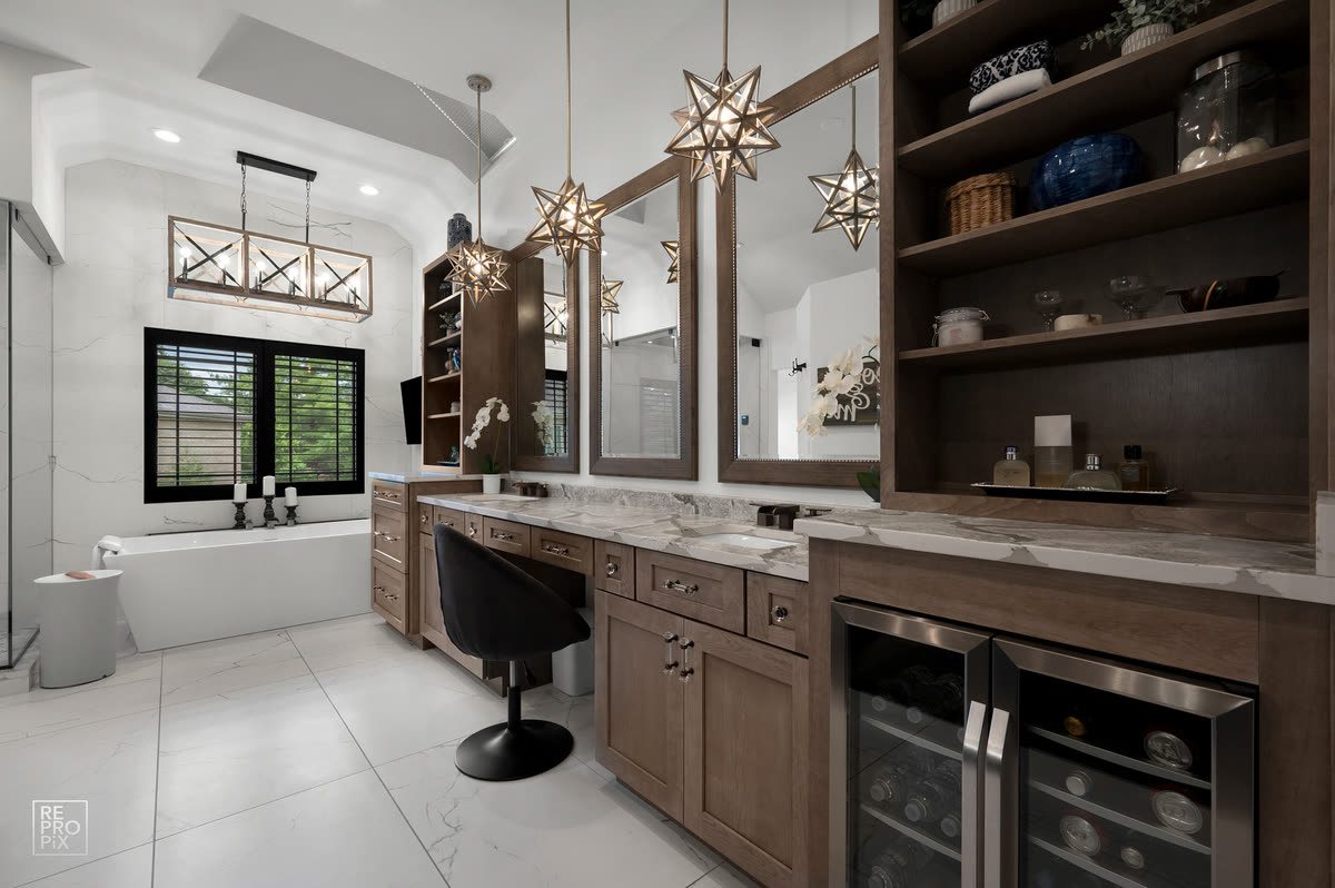 Primary bathroom with twin dark vanities, star pendant lights and a soaking tub — property photo