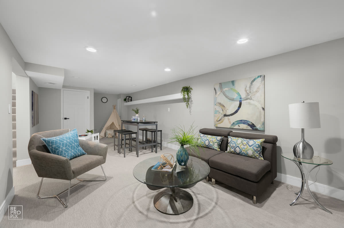 Lower-level sitting area with armchairs, a glass table and a corner play space — home interior photography