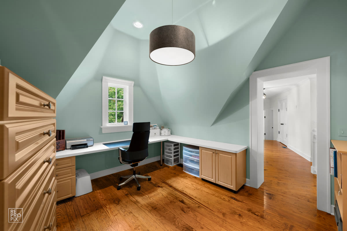 Green attic room with a sloped ceiling, built-in desk and drum pendant — home interior photography